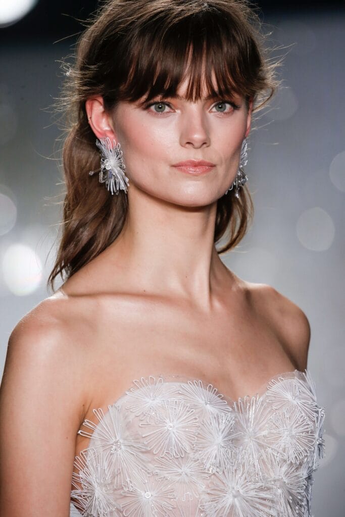 Woman in white dress with star earrings.
