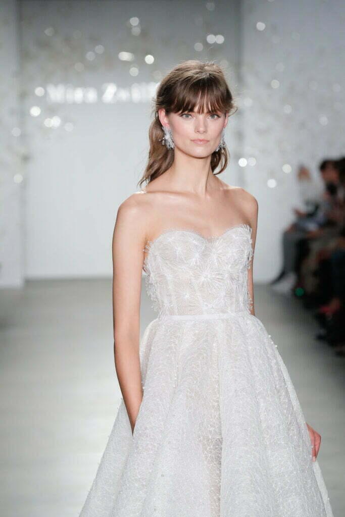 Model in strapless white gown on runway.