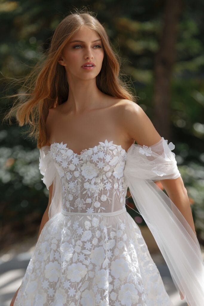 Woman in white lace wedding dress outdoors.