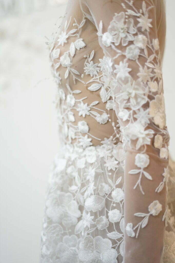White bridal gown with sheer, embroidered lace details.