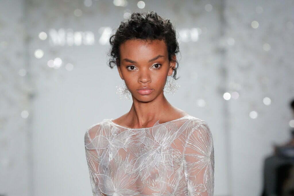 Model in sheer embroidered dress on runway.