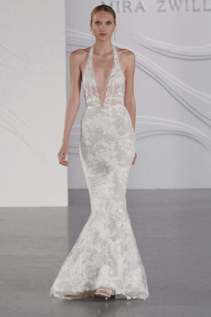 Woman models fitted lace mermaid wedding gown.