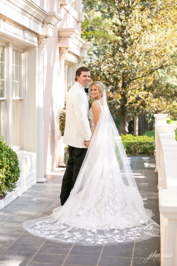 Bride and groom smiling, holding hands outside.