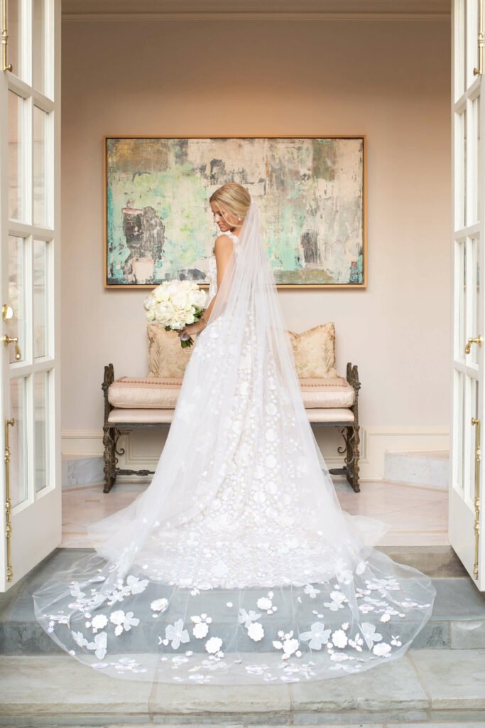 Bride with veil and bouquet, facing away.