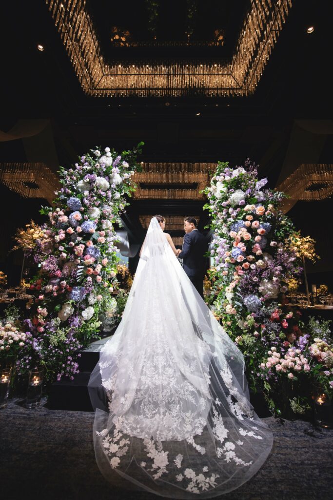 Bride and groom on floral-decorated wedding stage.
