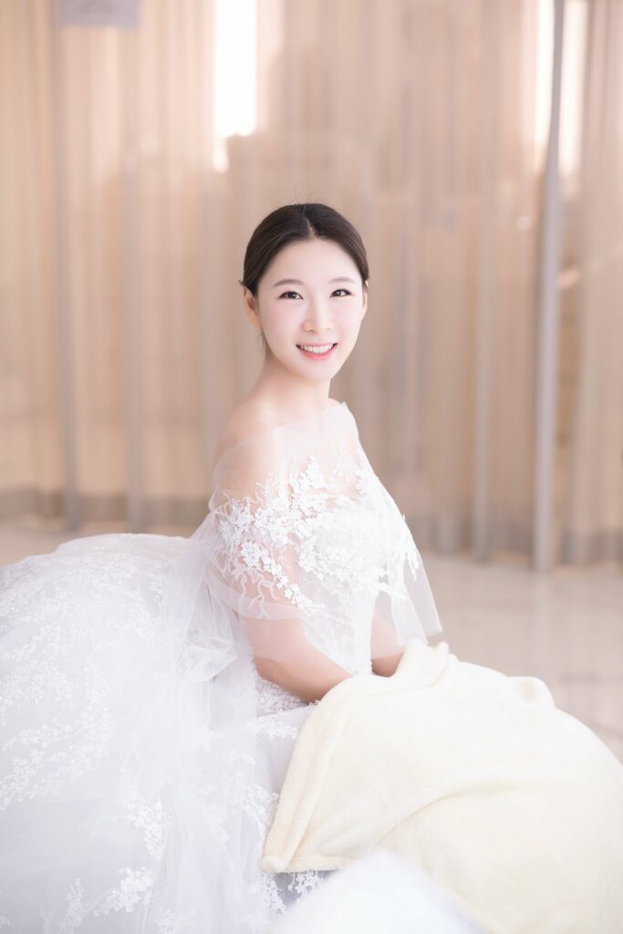 Woman in white lace wedding dress smiling.