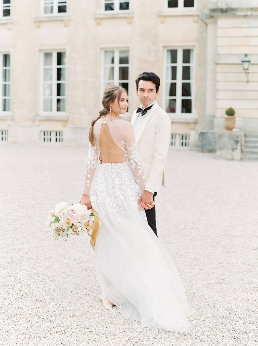 Bride and groom posing outdoors, historic building.