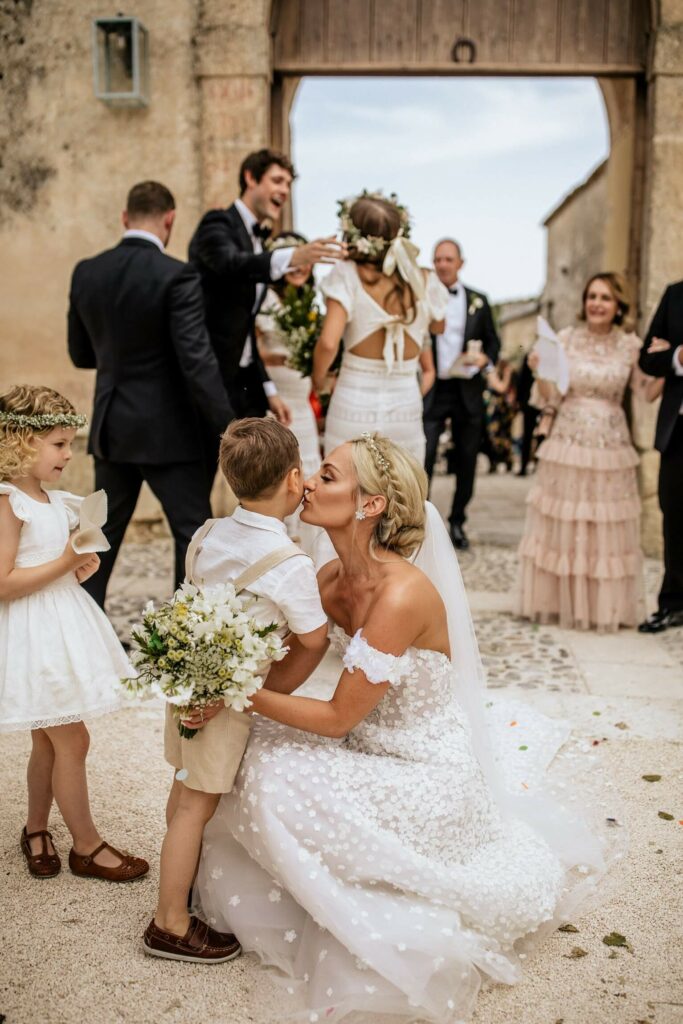 Bride kisses boy with flowers at wedding.