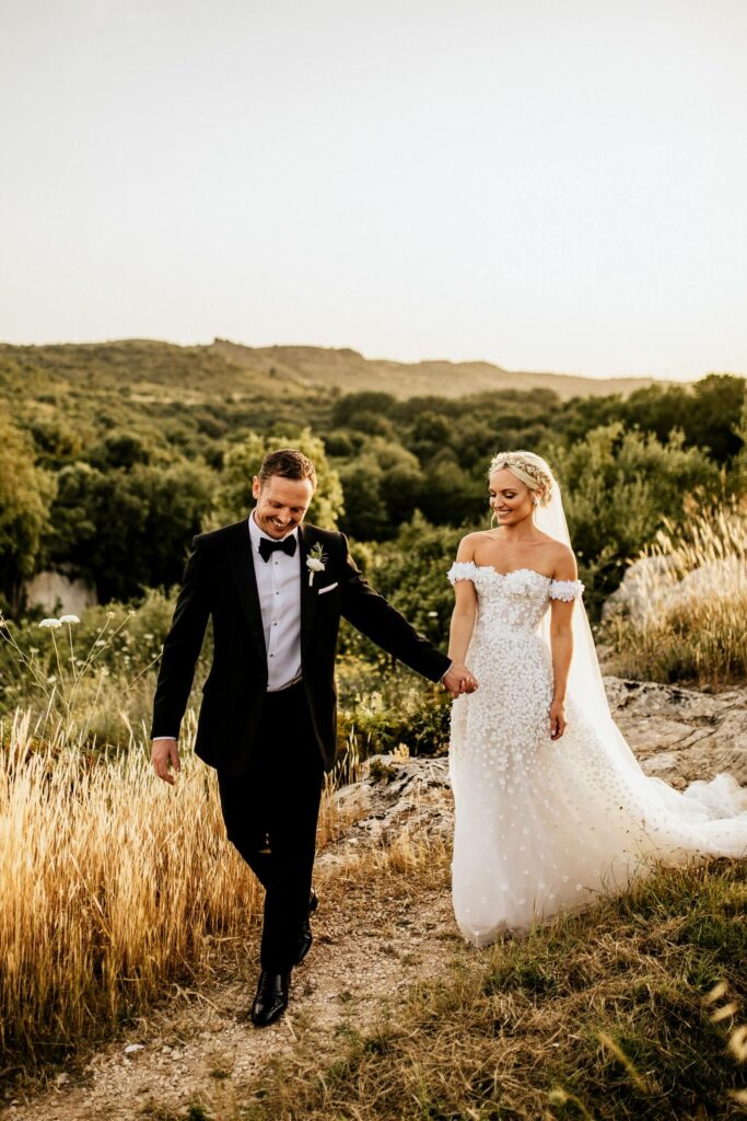 Bride and groom walk outdoors at sunset.