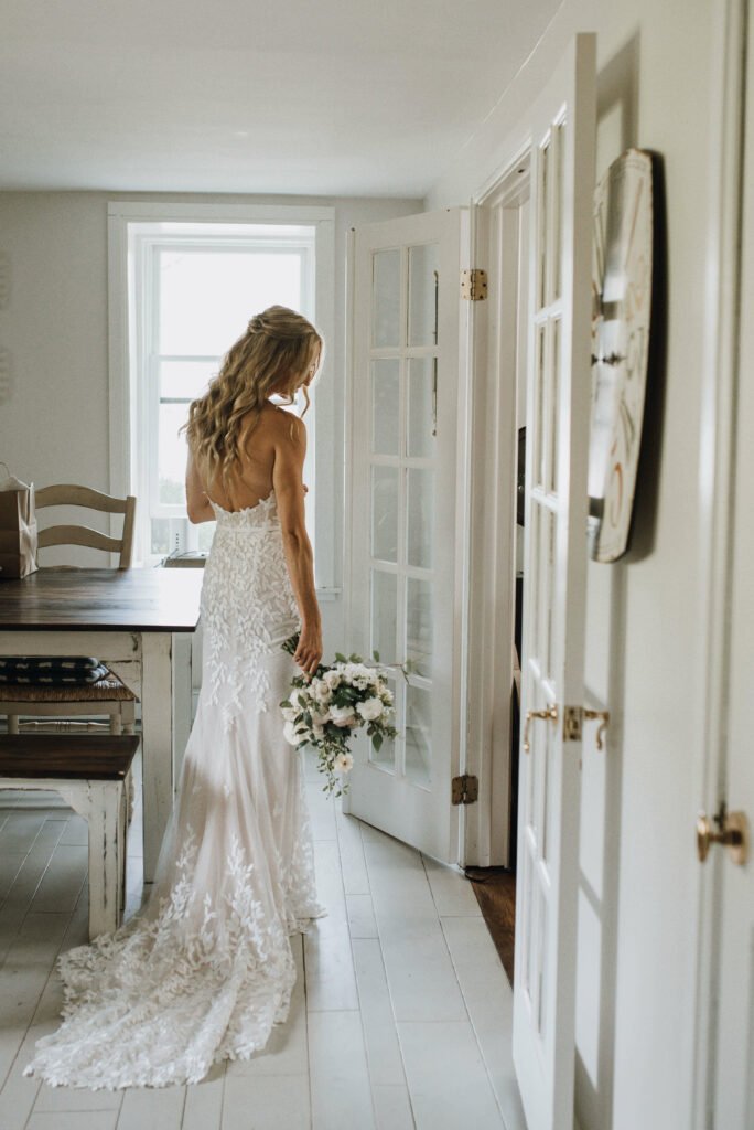 Bride with bouquet, back turned, lace dress.