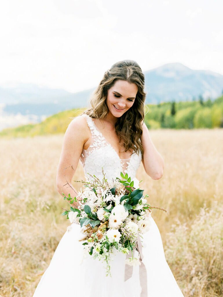 Bride in lace dress holding bouquet outdoors.