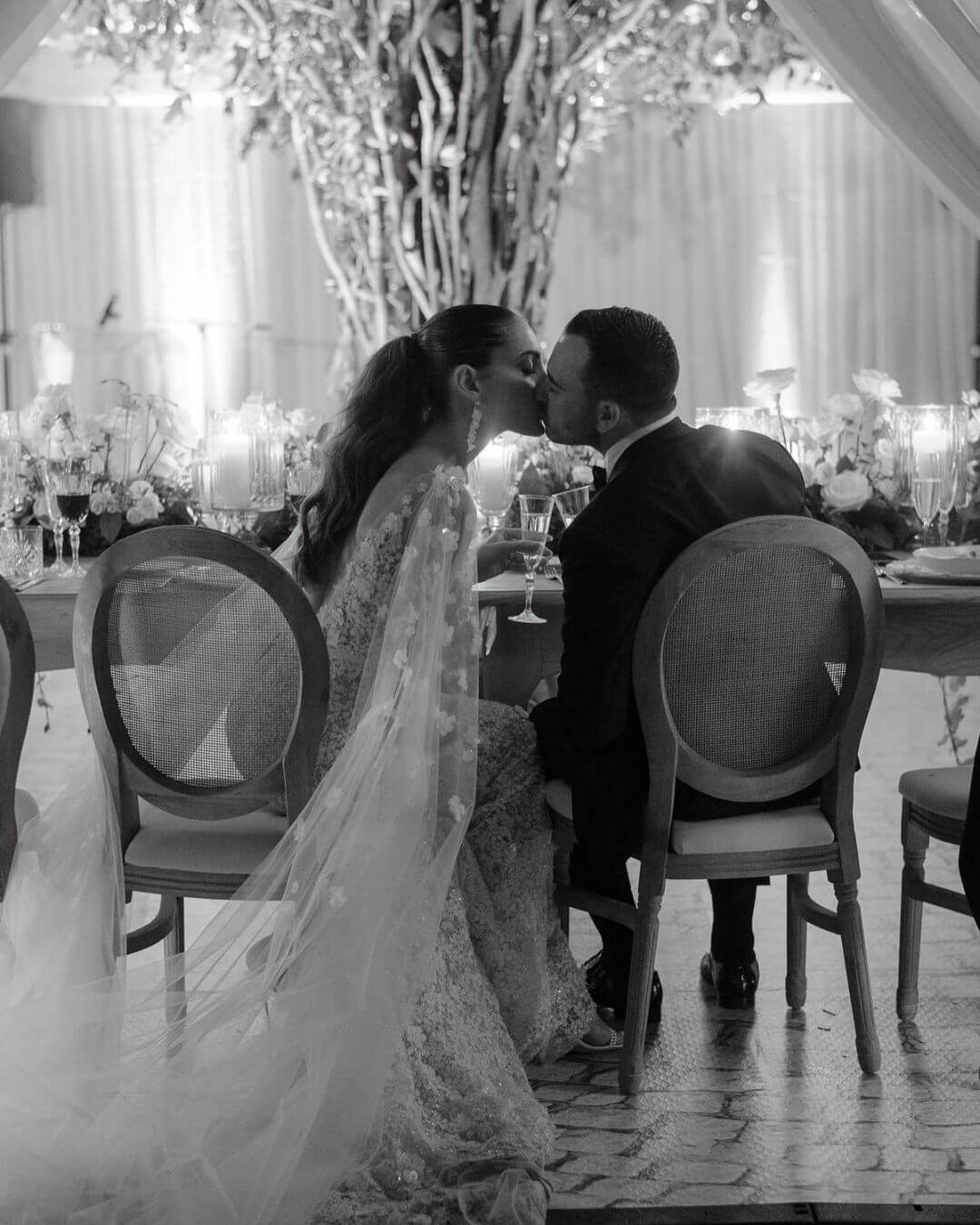 Bride and groom kiss at decorated table.