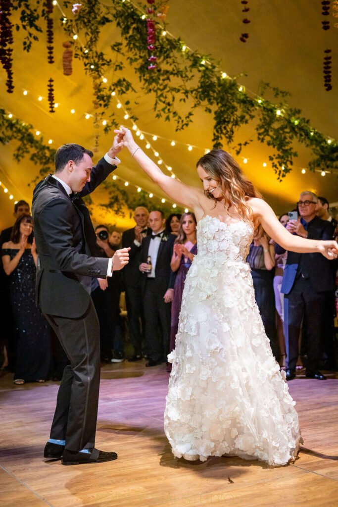 Bride and groom dancing under festive lights.