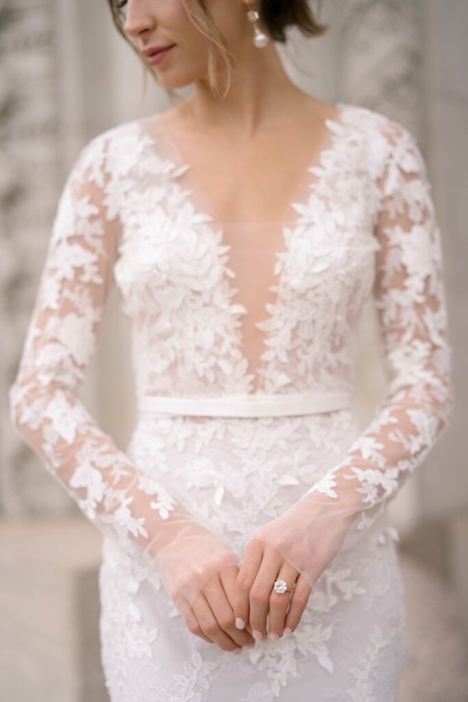 Bride in lace dress shows engagement ring.