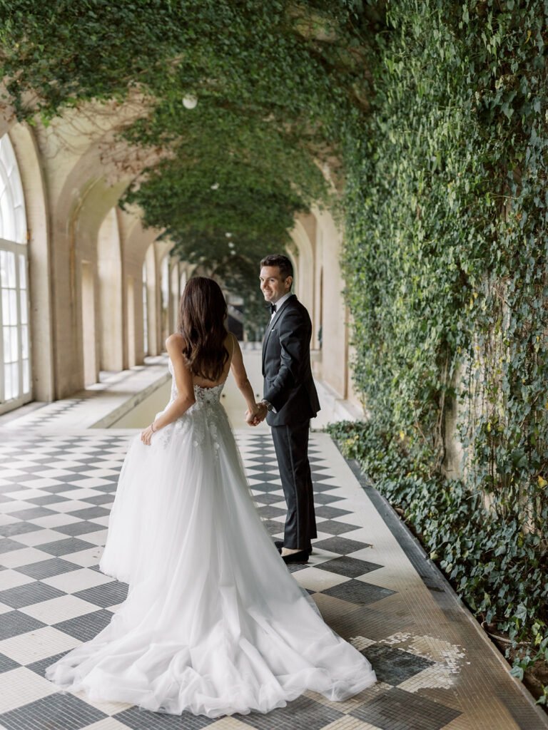 Bride and groom holding hands on checkered floor.