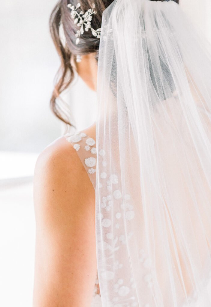 Bride in floral dress and veil, back view.