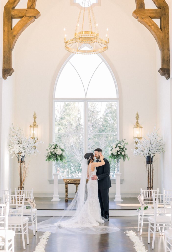 Bride and groom embrace in elegant chapel.