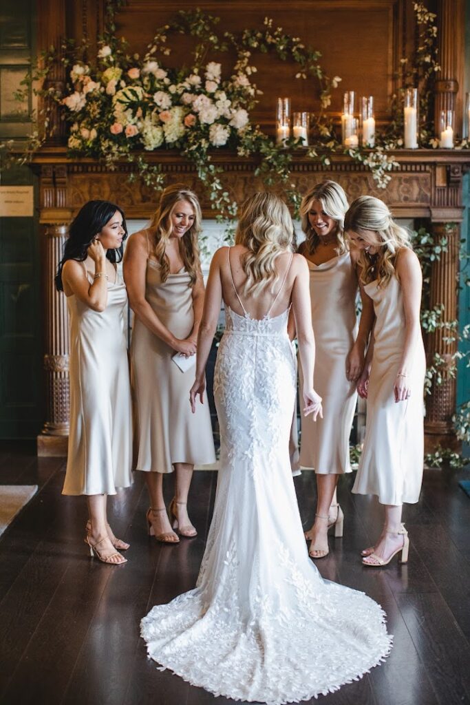 Bride in lace gown with smiling bridesmaids.