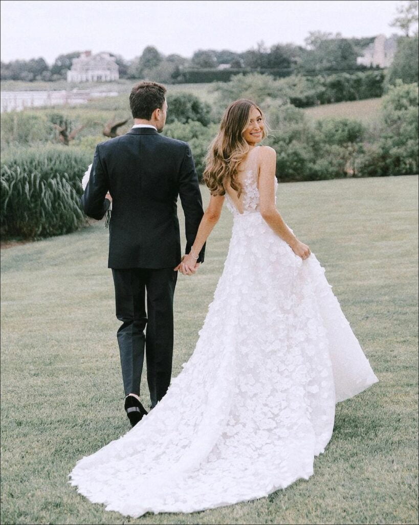 Bride and groom walking on lawn, smiling.