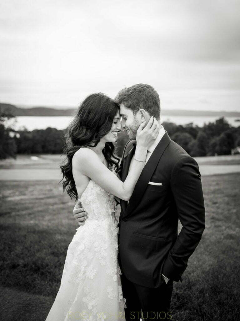 Bride and groom embrace outdoors, smiling.