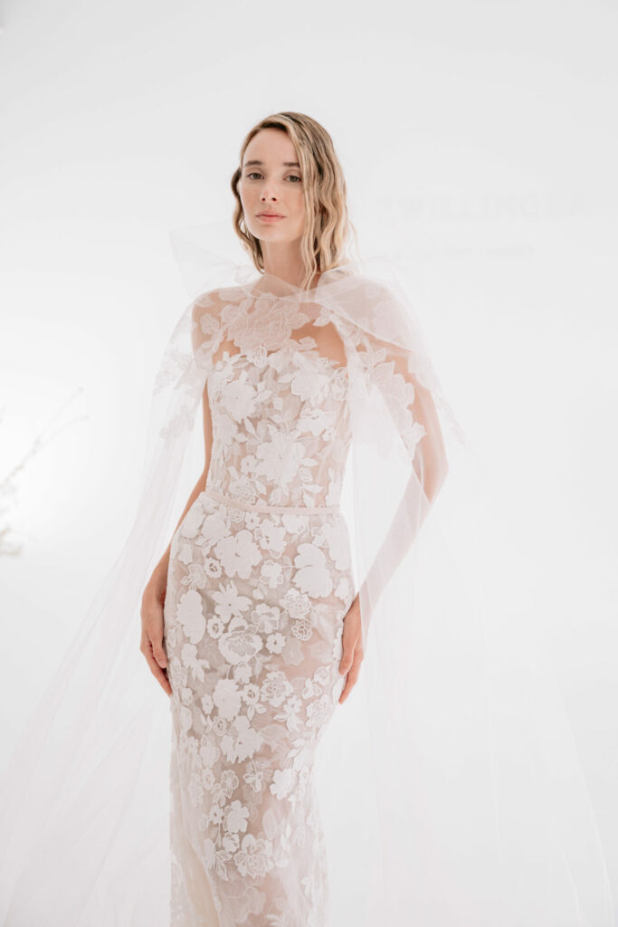 Woman in sheer lace wedding dress with cape.