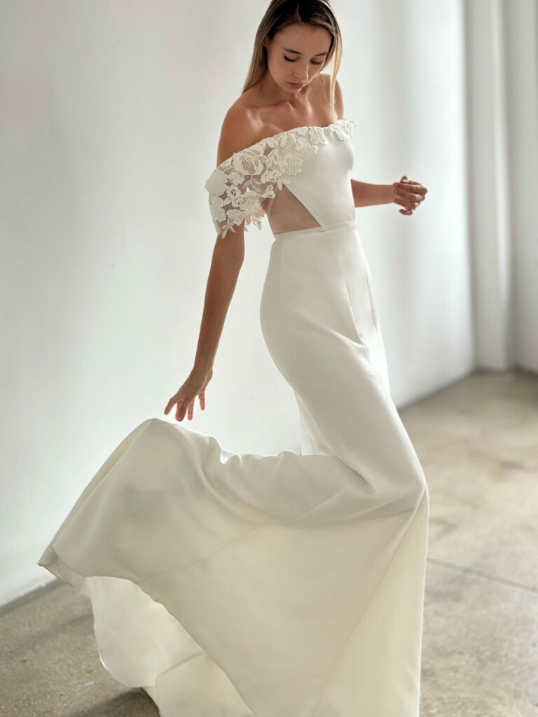 Woman twirls in white lace gown indoors.
