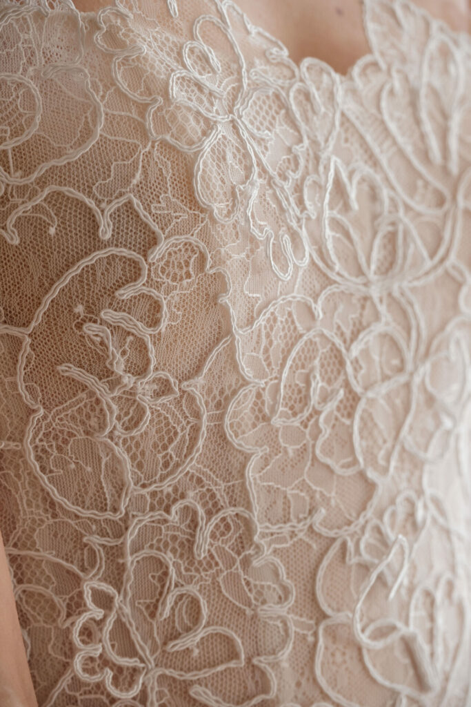 Detailed white lace floral embroidery on nude fabric.
