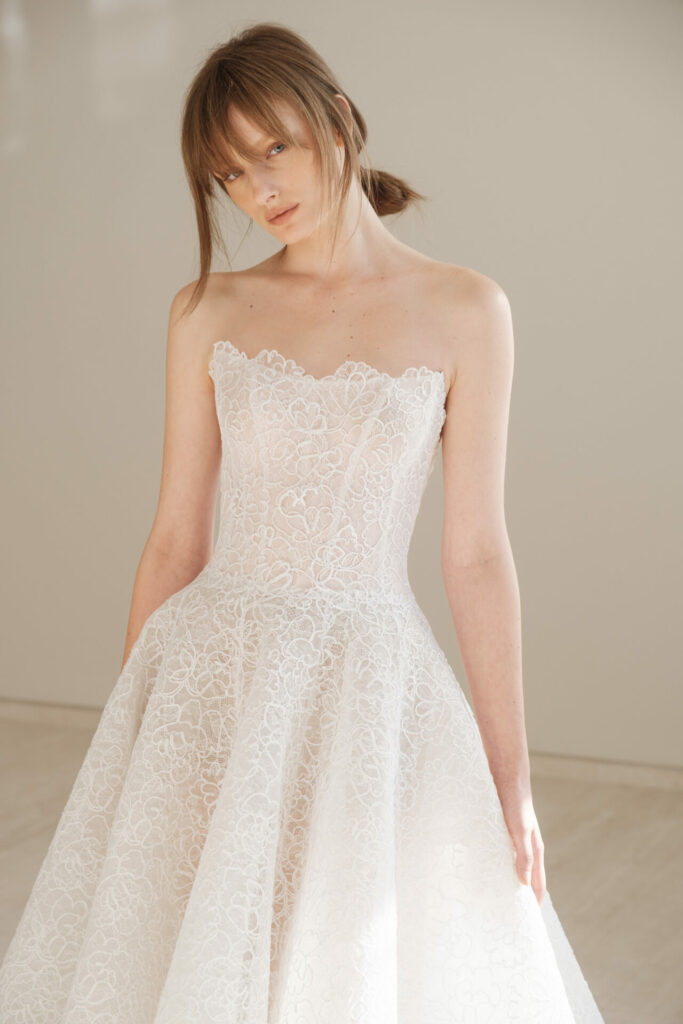 Bride in white lace dress, looking sideways.