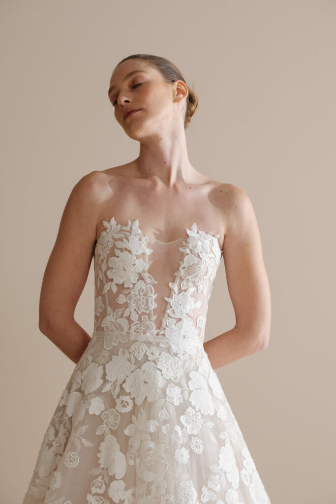 Woman in strapless lace wedding dress posing.