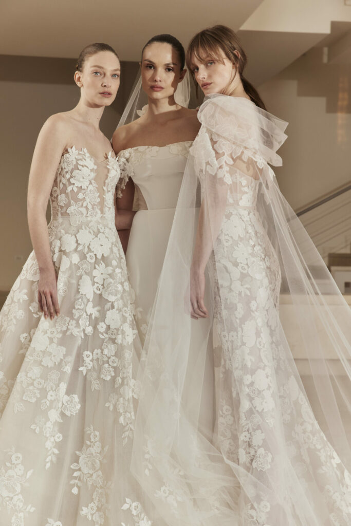 Three women in white lace wedding dresses indoors.