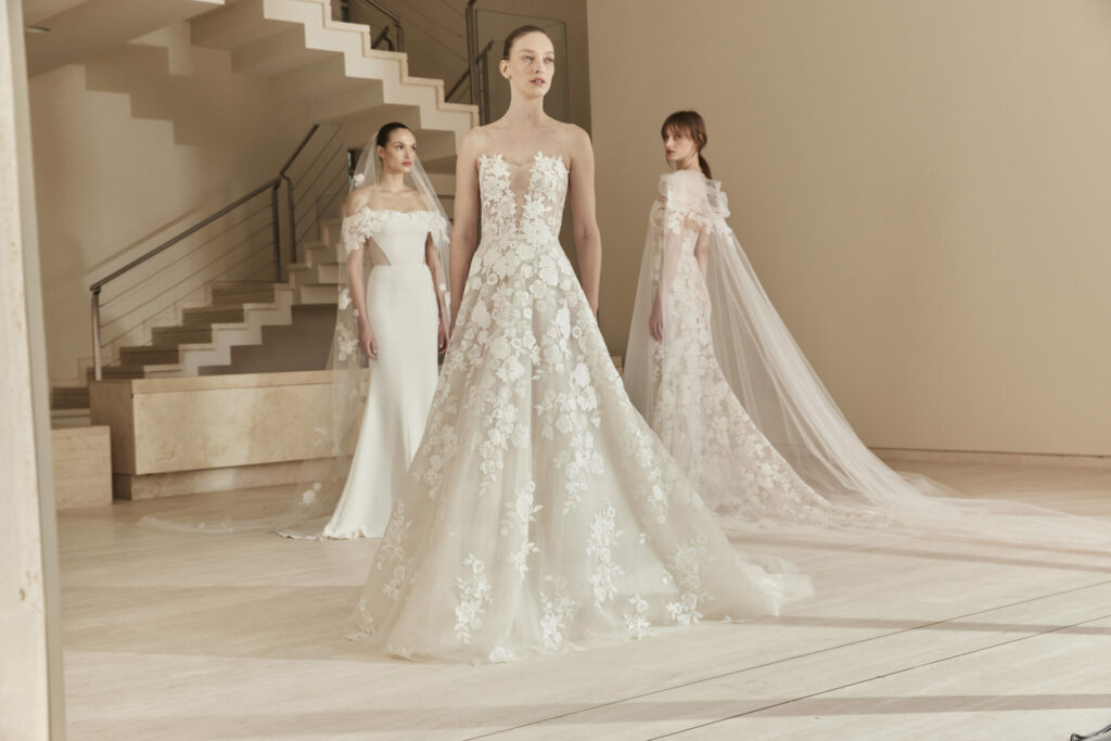 Three women in white lace wedding dresses indoors.