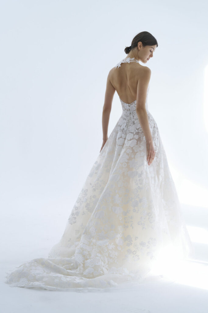Woman in backless lace gown with train, posing.