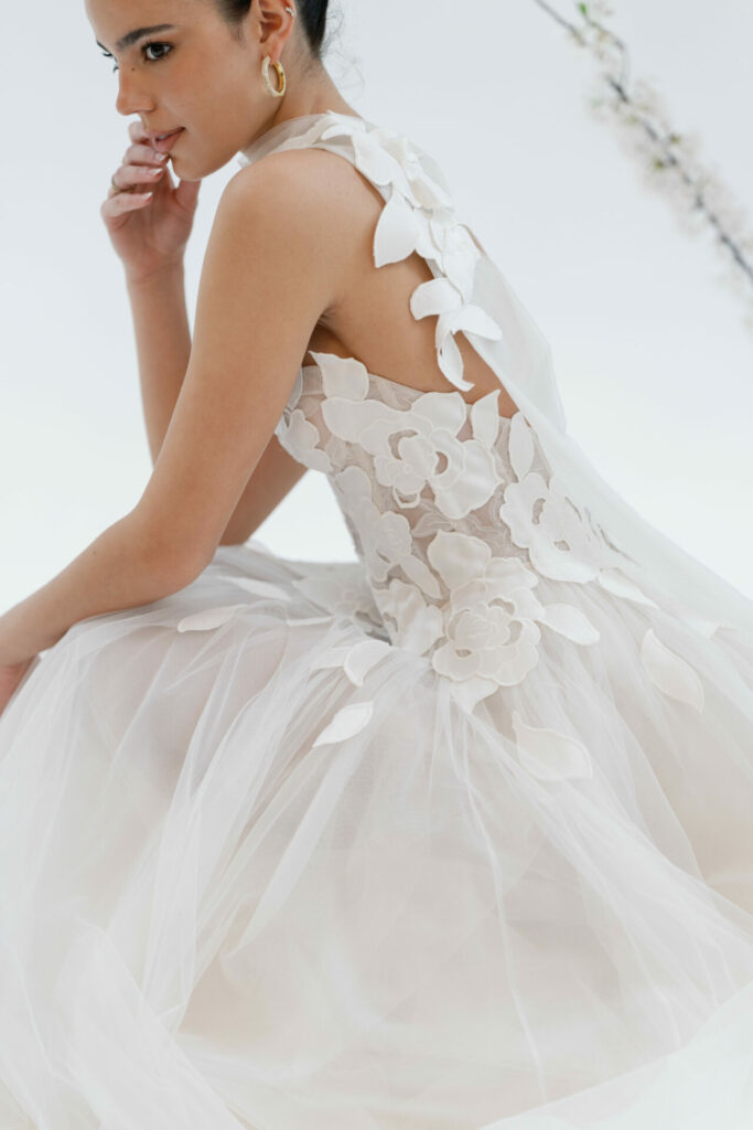 Woman in floral tulle dress, chin in hand.