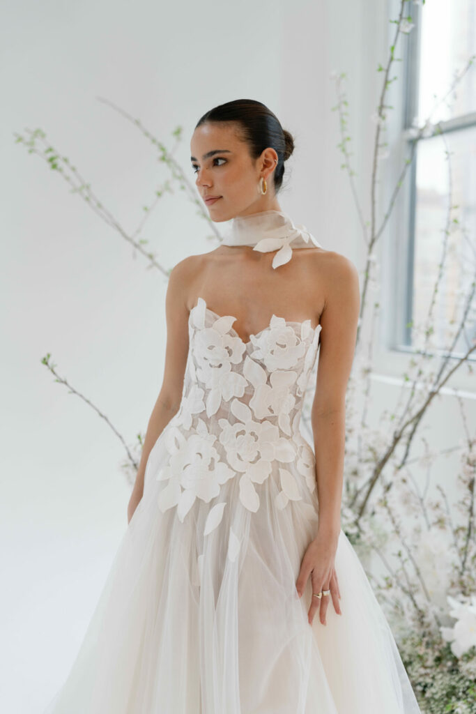 Woman in floral wedding dress by windows.