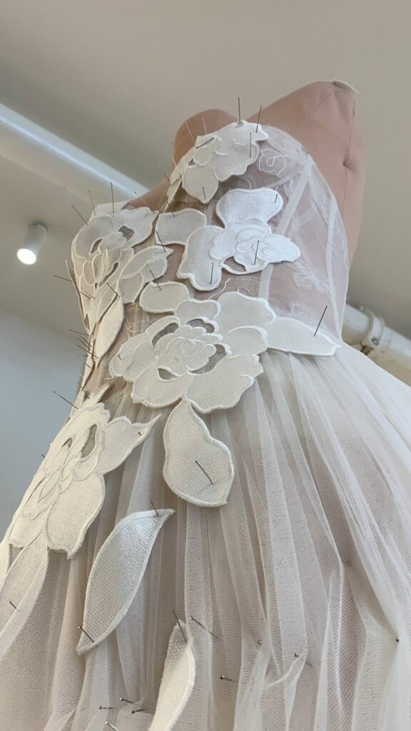 Dress form with pinned white floral gown.