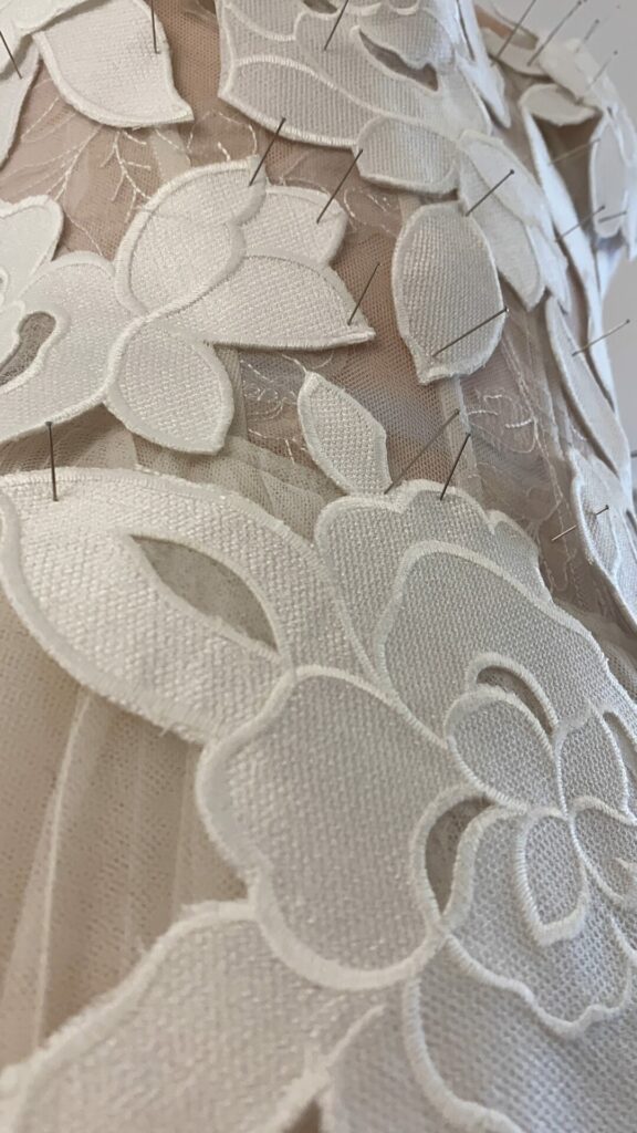 White lace appliqué pinned on sheer fabric.