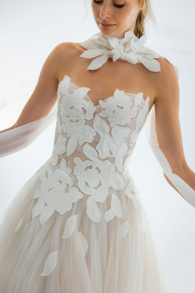 Woman in sheer floral gown against white background.