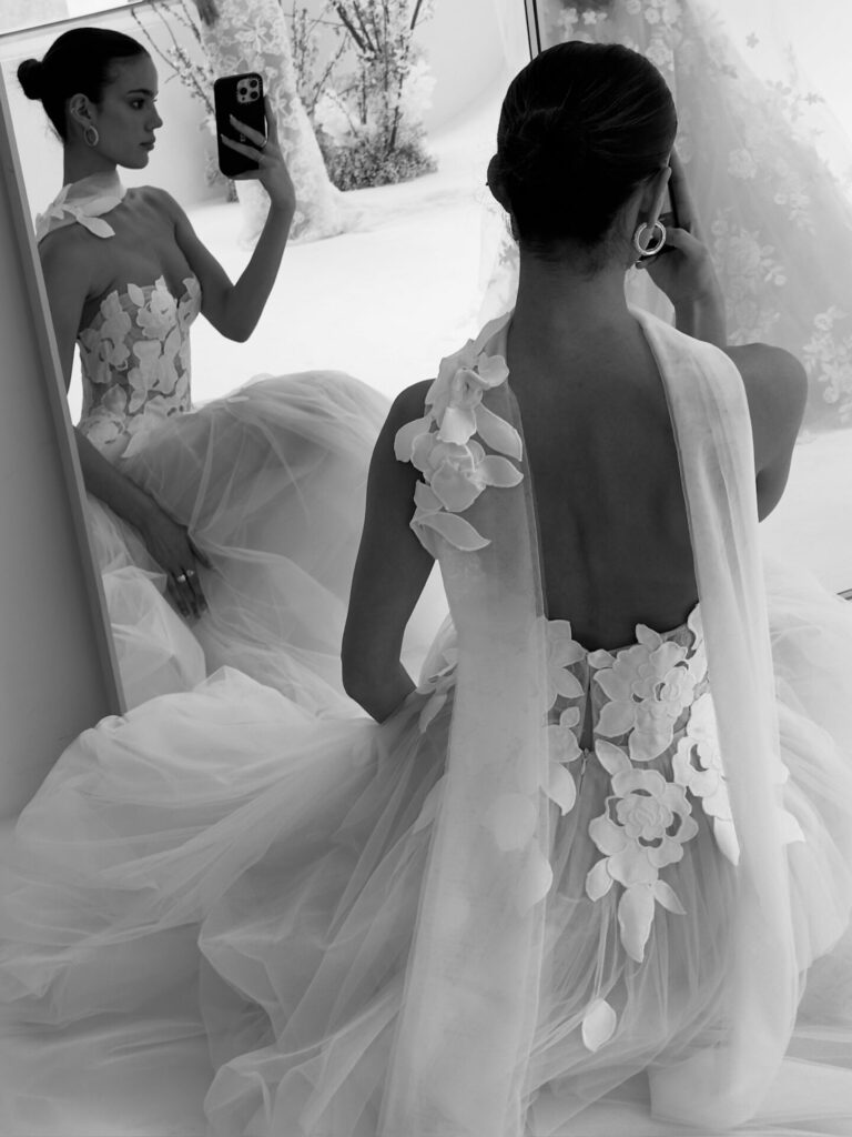 Woman in 3D floral gown, mirror selfie.