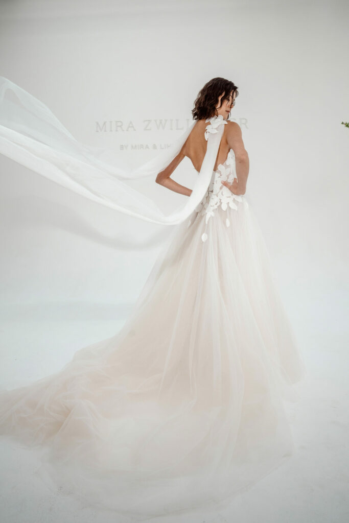 Bride in white gown looks over shoulder.