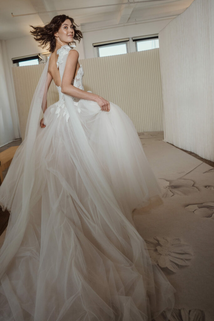 Woman twirling in white wedding dress indoors.