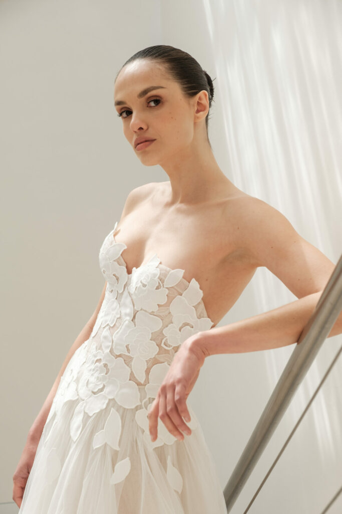 Woman in strapless white wedding dress posing.
