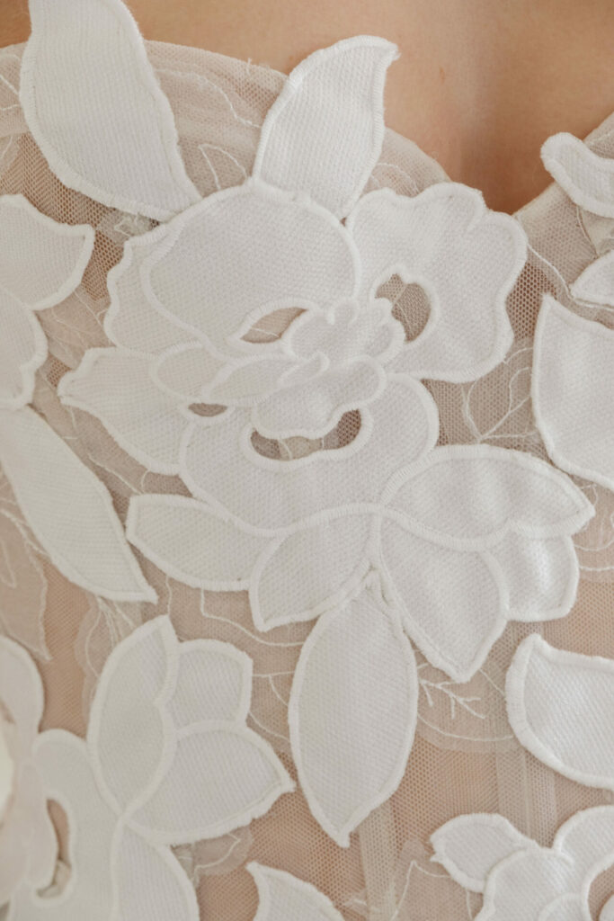 Sheer fabric with layered white floral embroidery.