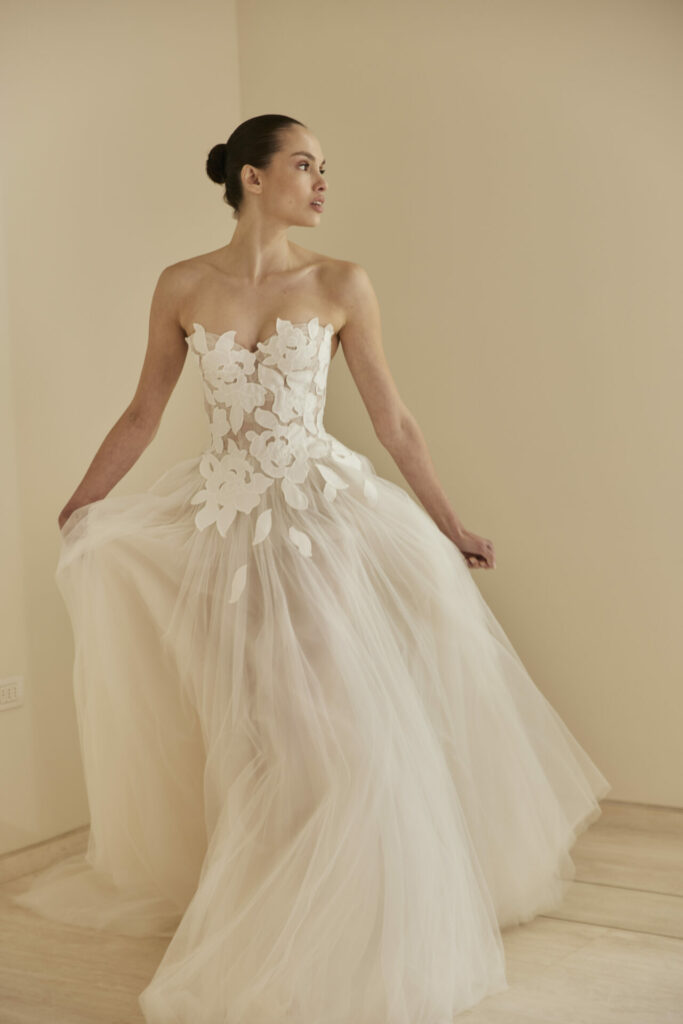 Woman in floral tulle gown holds dress.