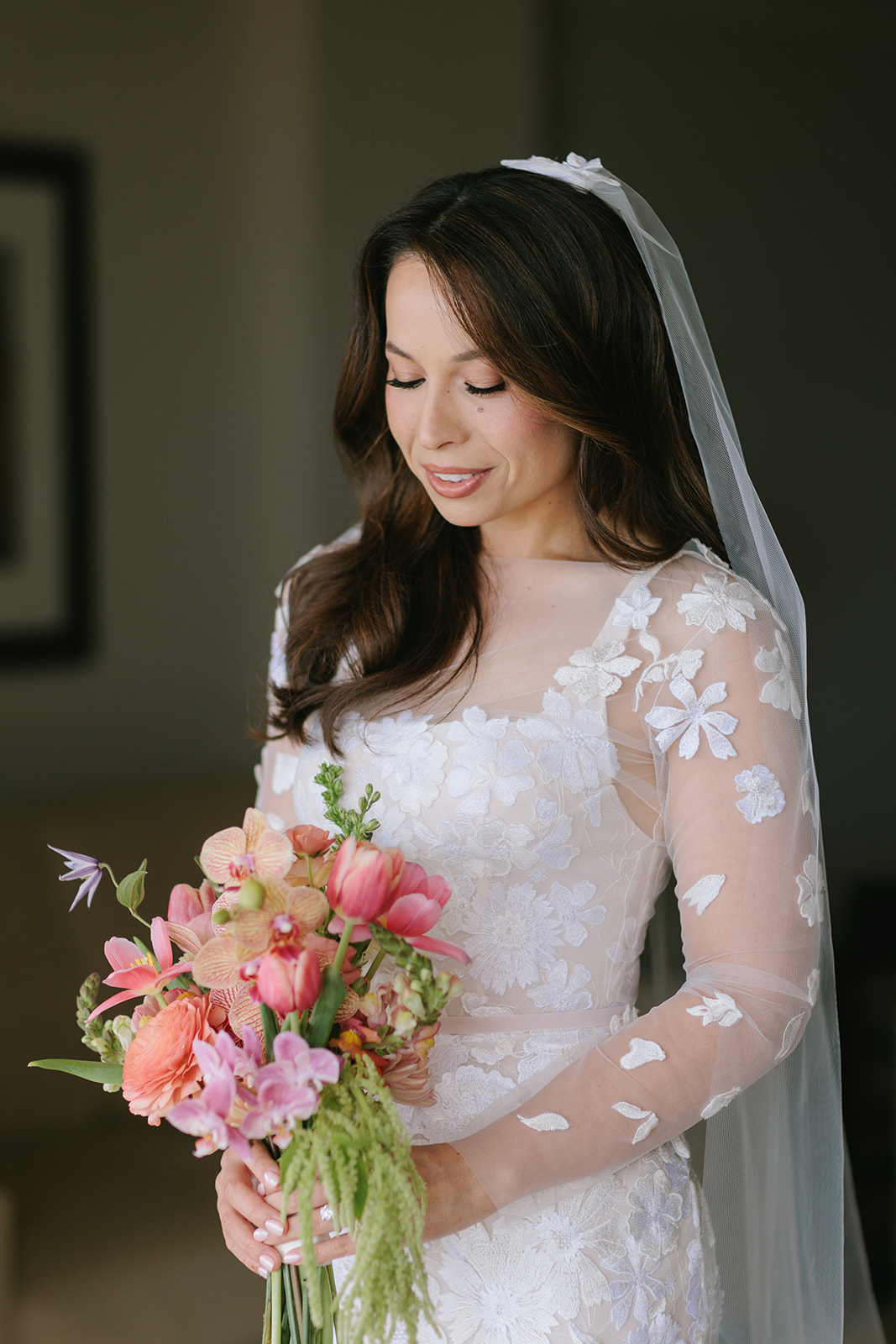 Bride in floral dress holding colorful bouquet.