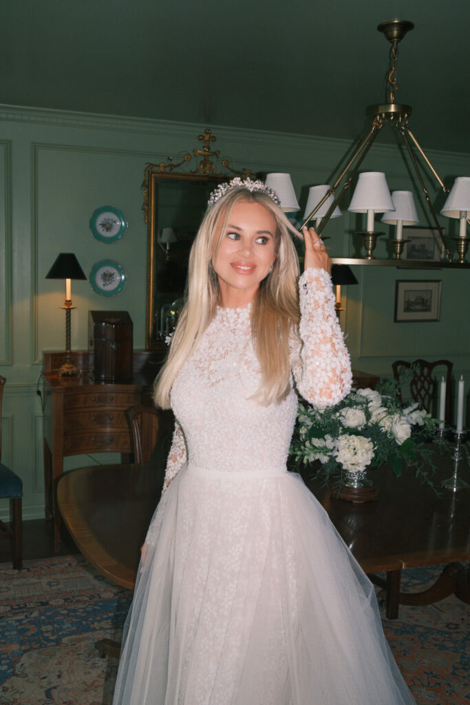 Bride in lace dress smiles in elegant room.