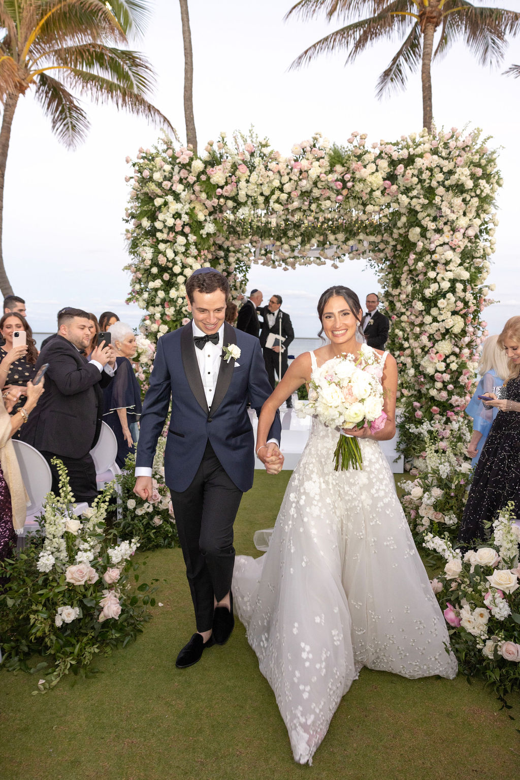 Bride and groom walk hand-in-hand, smiling.