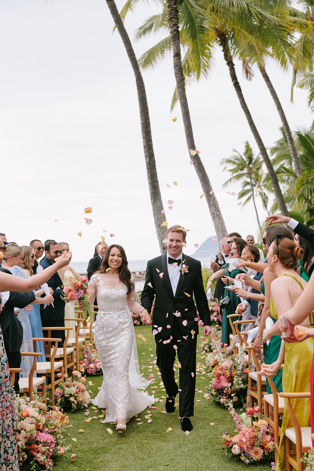 Bride and groom walk joyfully amid tropical wedding.
