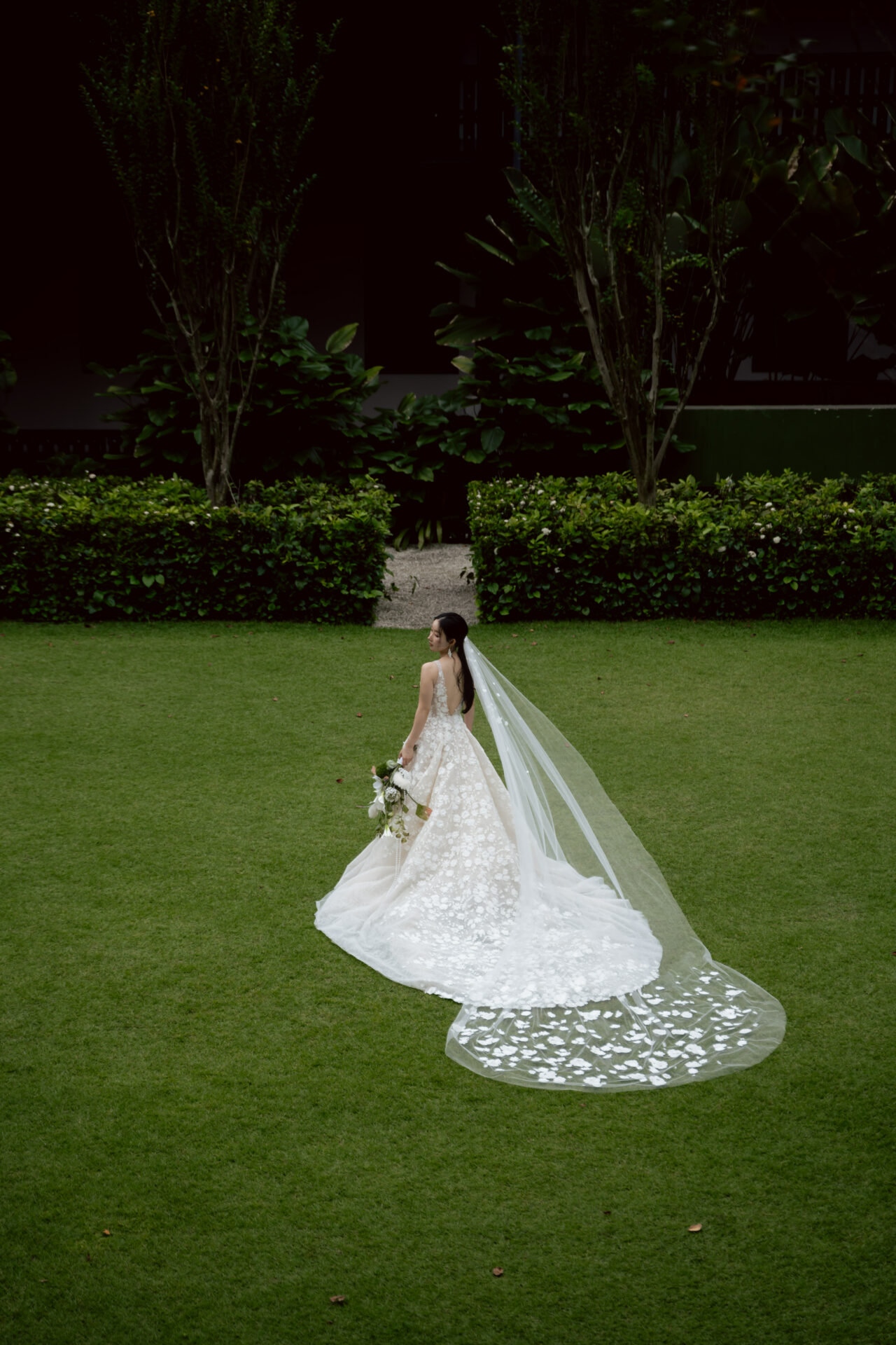 Bride in white gown walks on grass.
