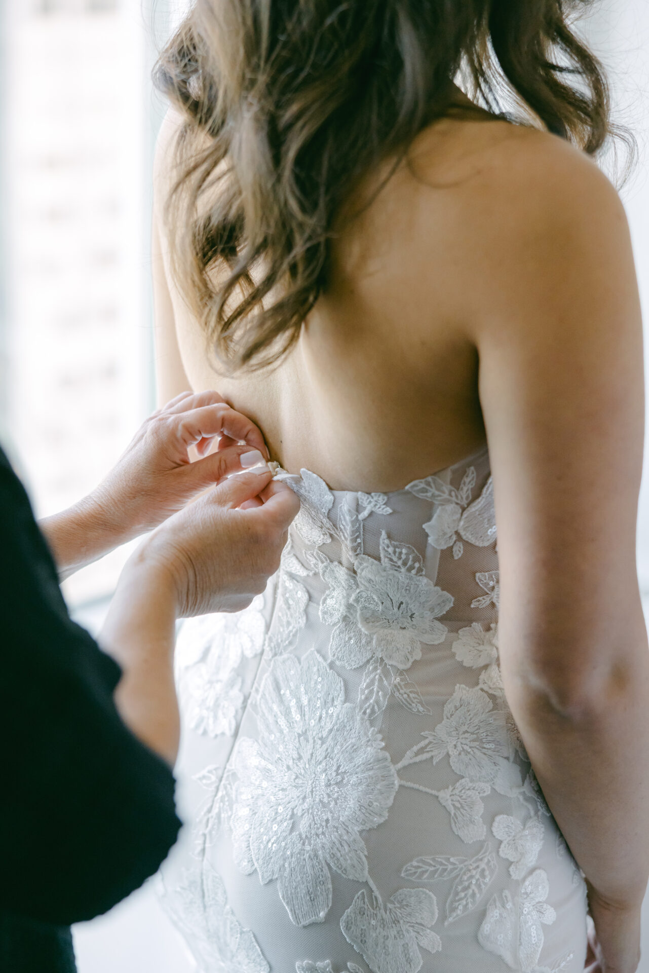 Fastening strapless lace wedding dress, natural light.