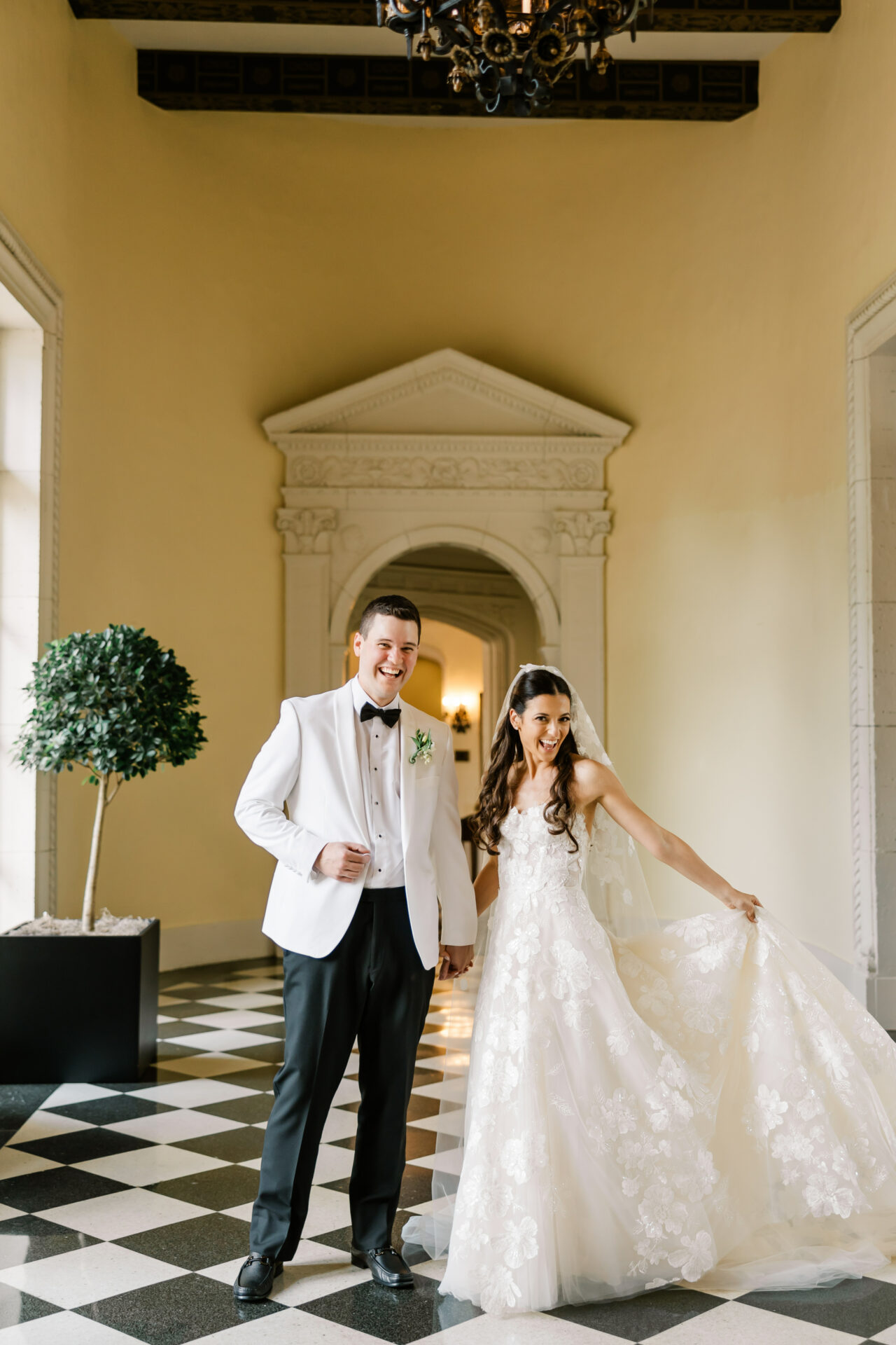 Bride and groom smiling in elegant hallway.